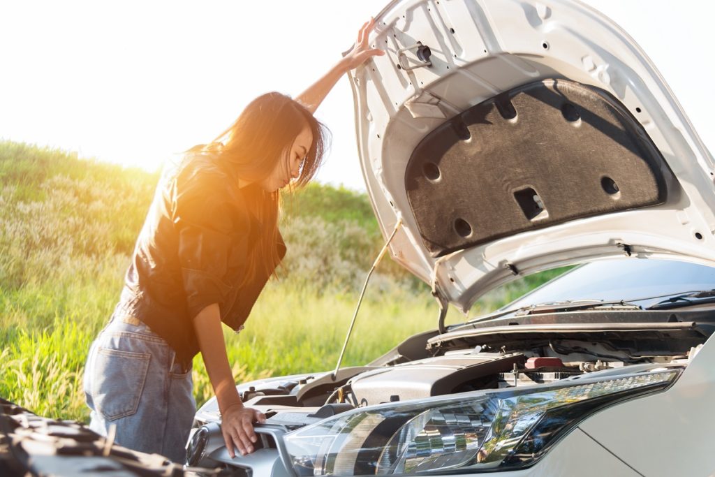 Woman checking her overheating car engine