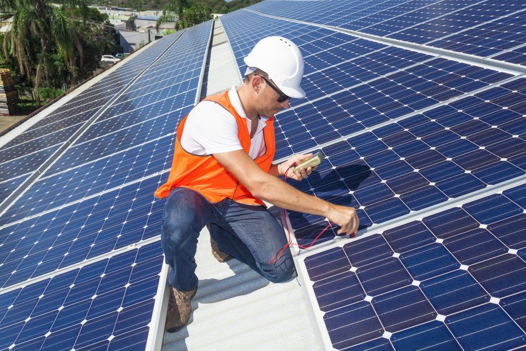  technician checking solar panels on roof