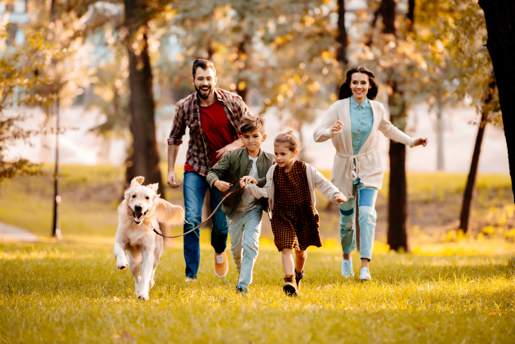 a happy family running outdoors with their pet dog