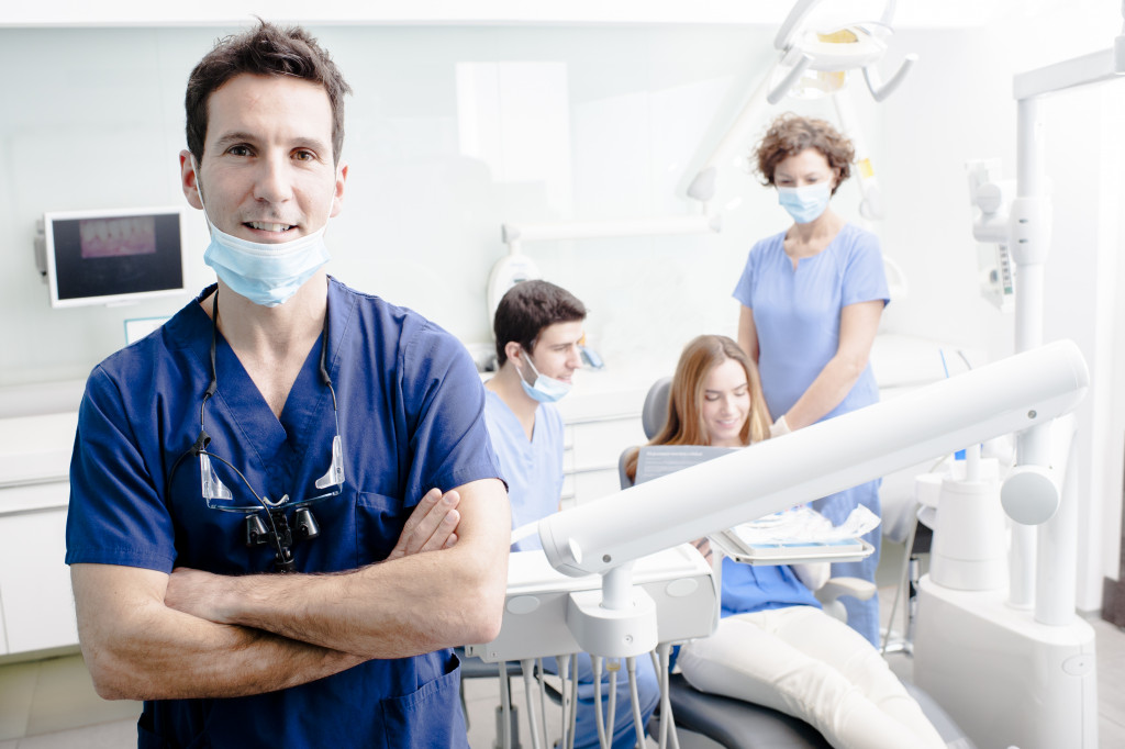 A dentist in a dental clinic with his team looking after a patient