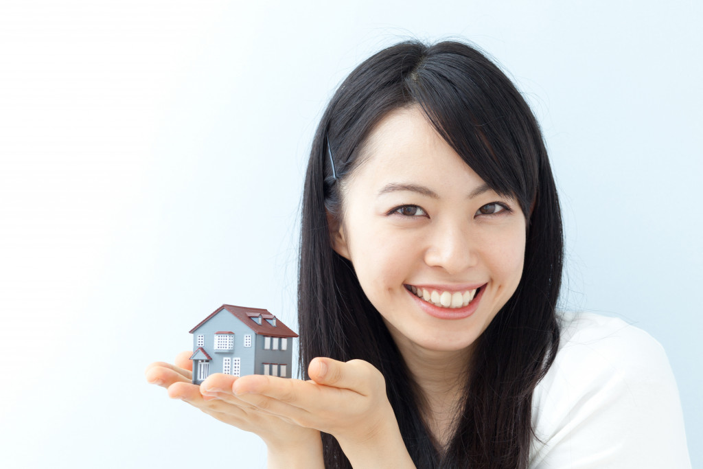 a woman holding a miniature of a small house