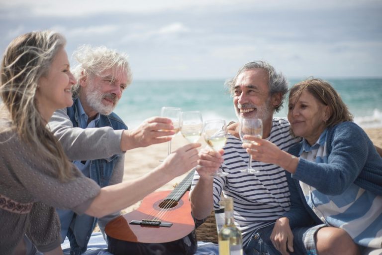 Retired seniors drinking wine by the beach