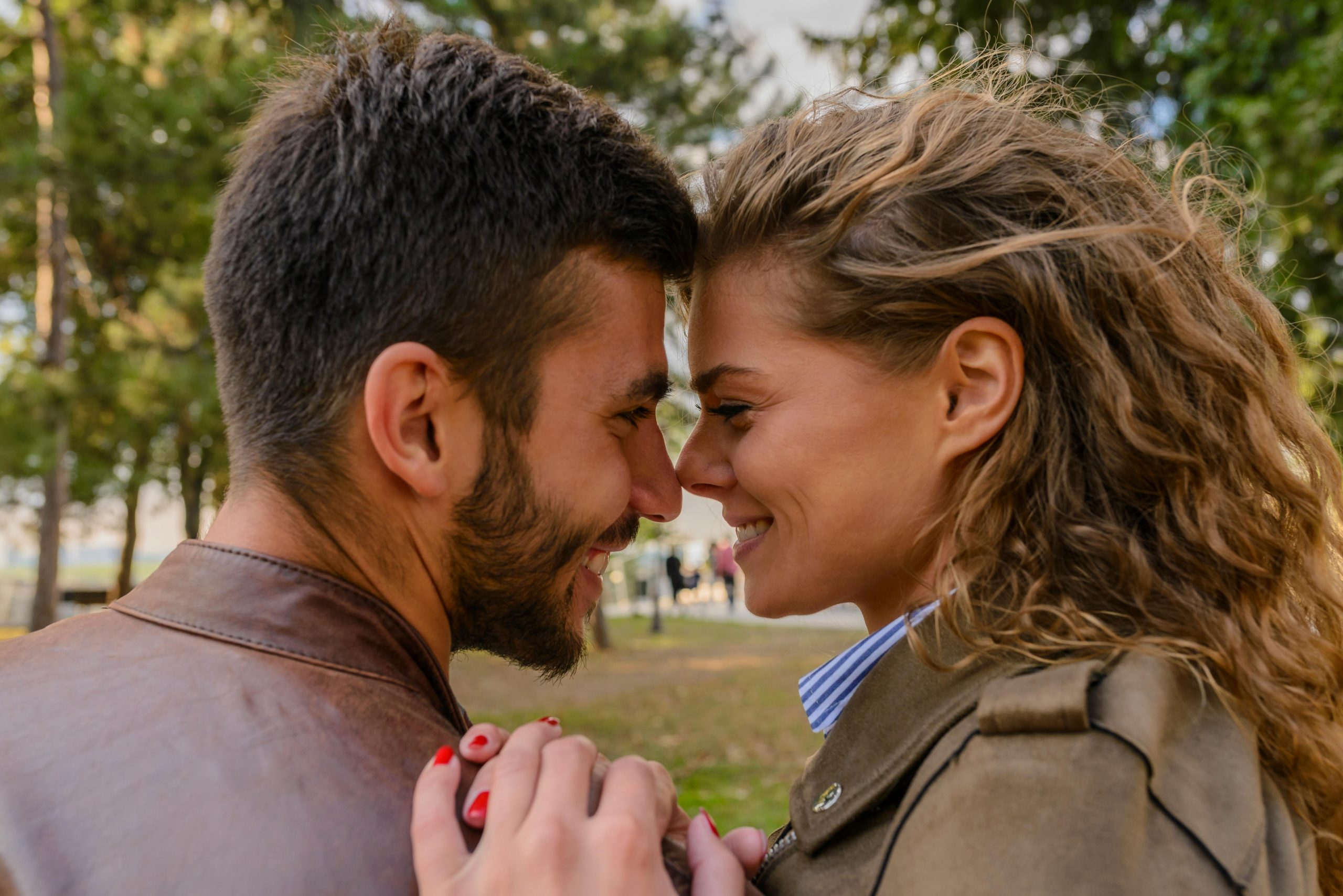 couple standing nose to nose, holding hands